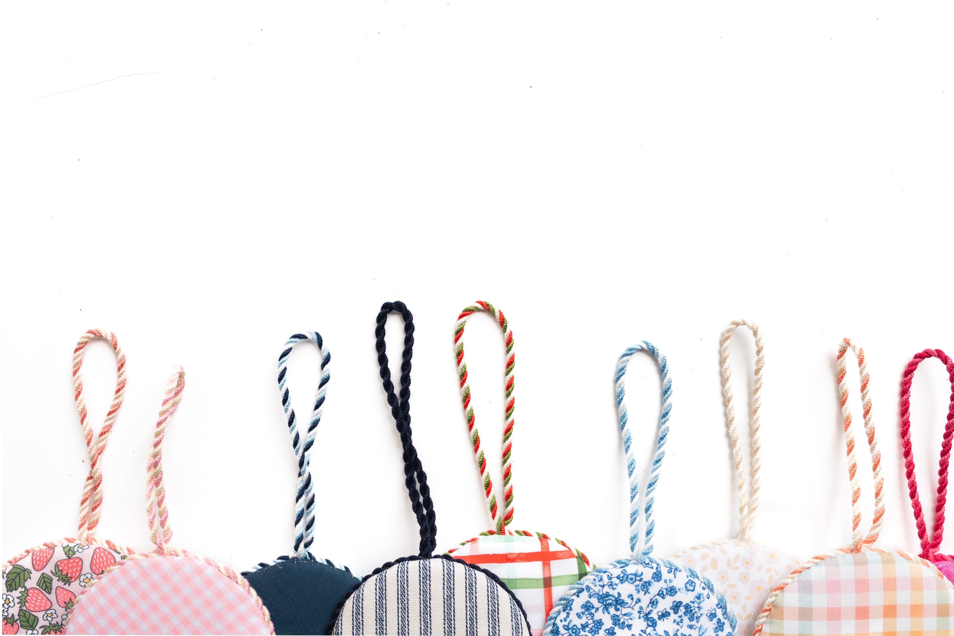 Hand-finished needlepoint ornaments by Sudbrook Finishing House featuring curated fabrics and matching cording.